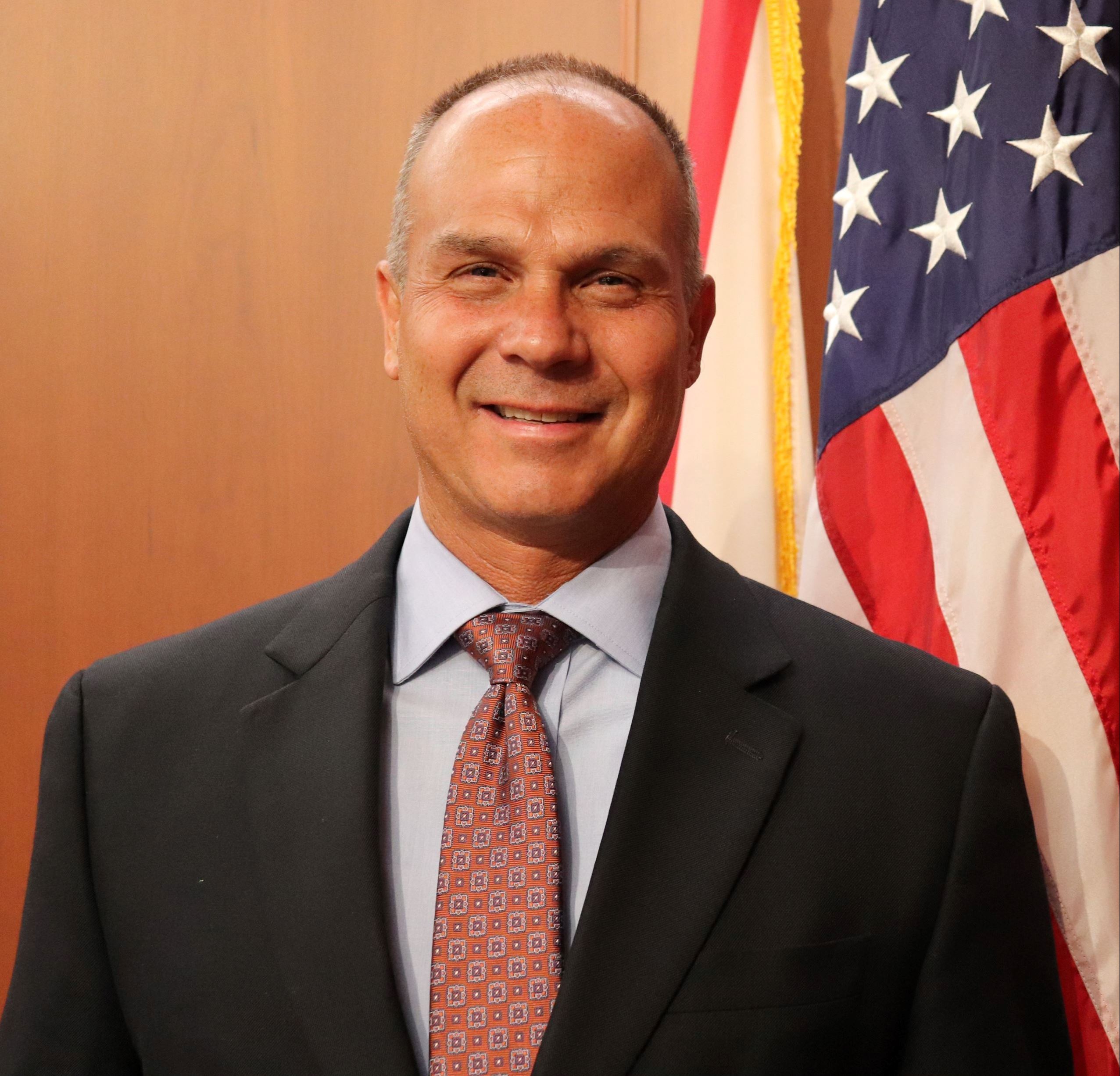Council Member Matt Johnson standing in front of American Flag in Council Chambers.