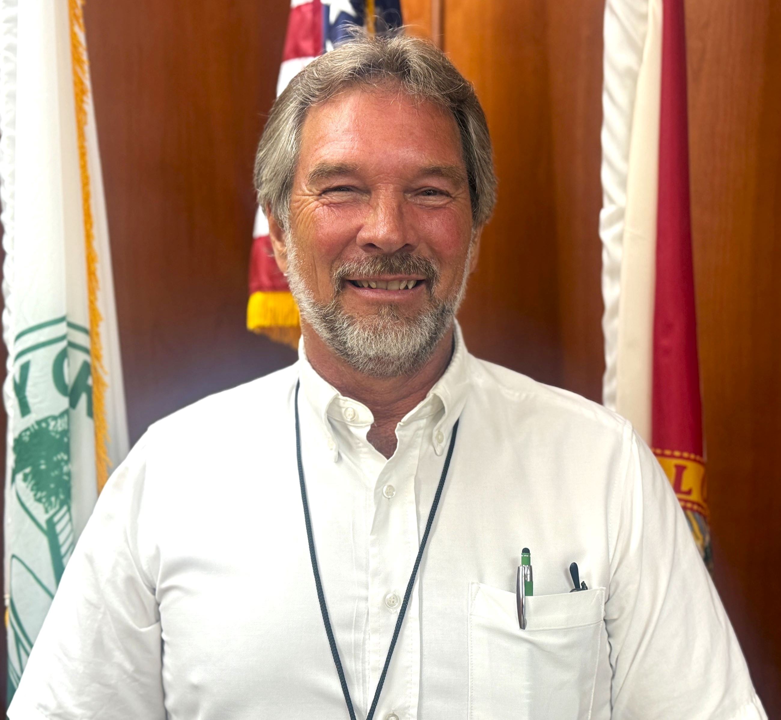 Council Member Stutts standing in front of American Flag in Council Chambers.